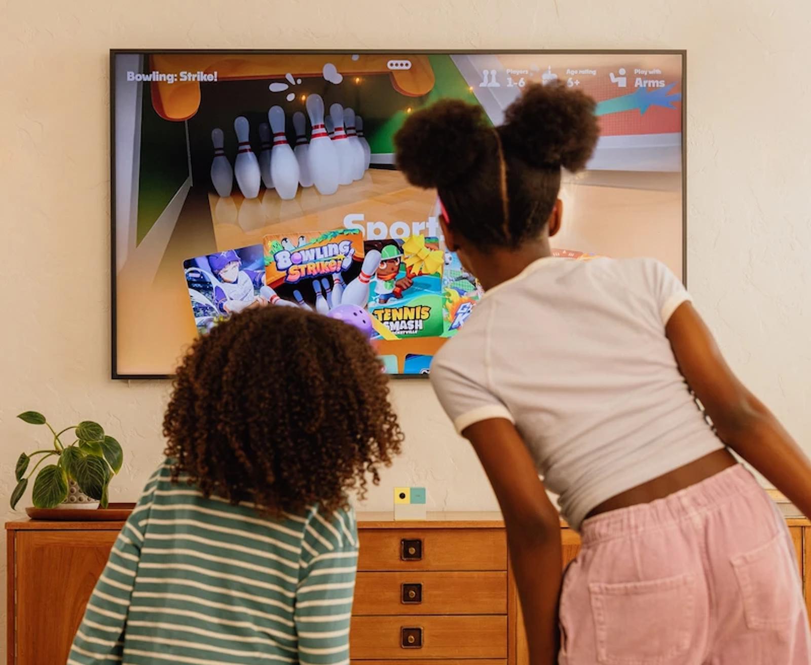 2 girls looking at game tiles on tv