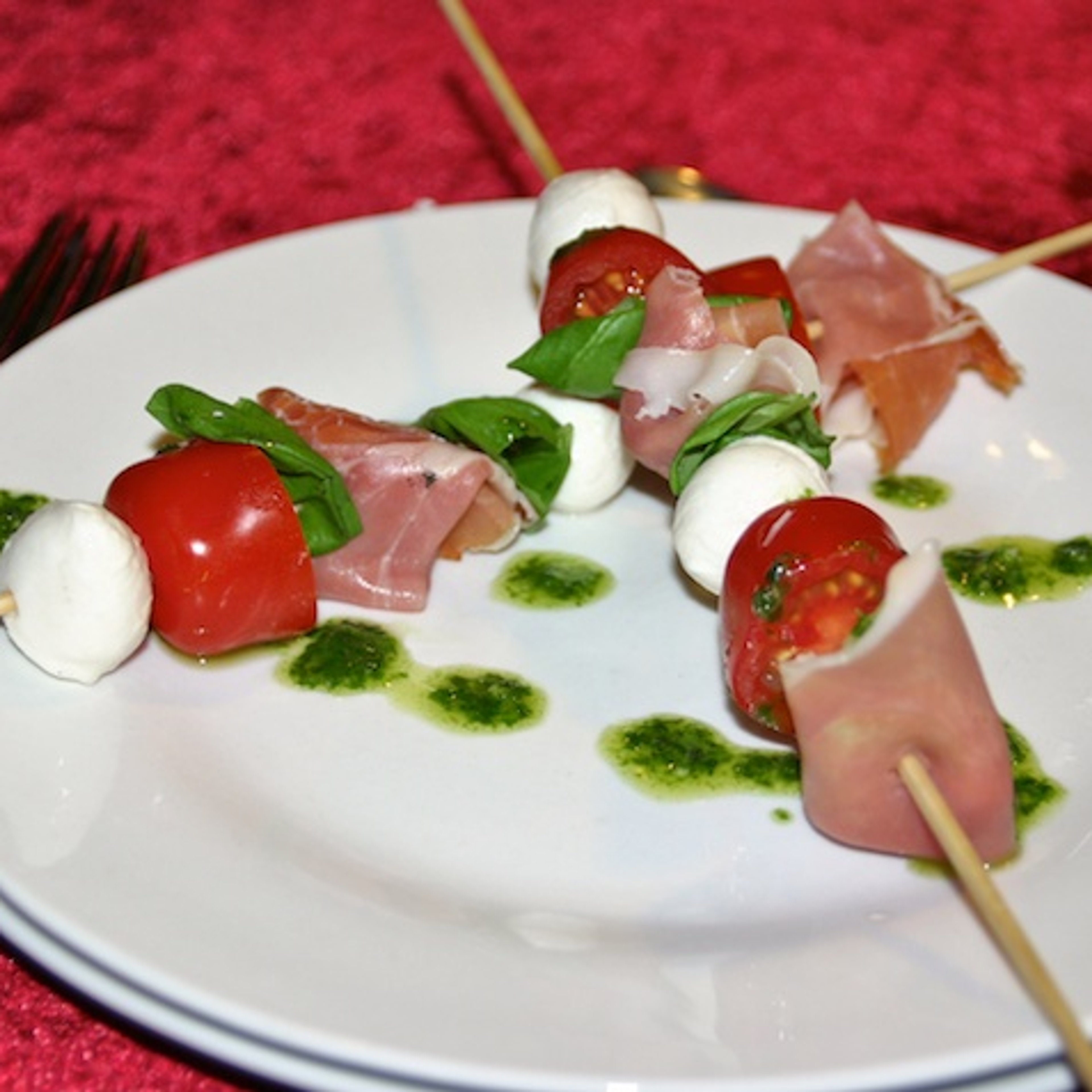 Insalata caprese con prosciutto e olio di pesto su un bastone - eller tomatsalat med skinke og pestoolie på pind