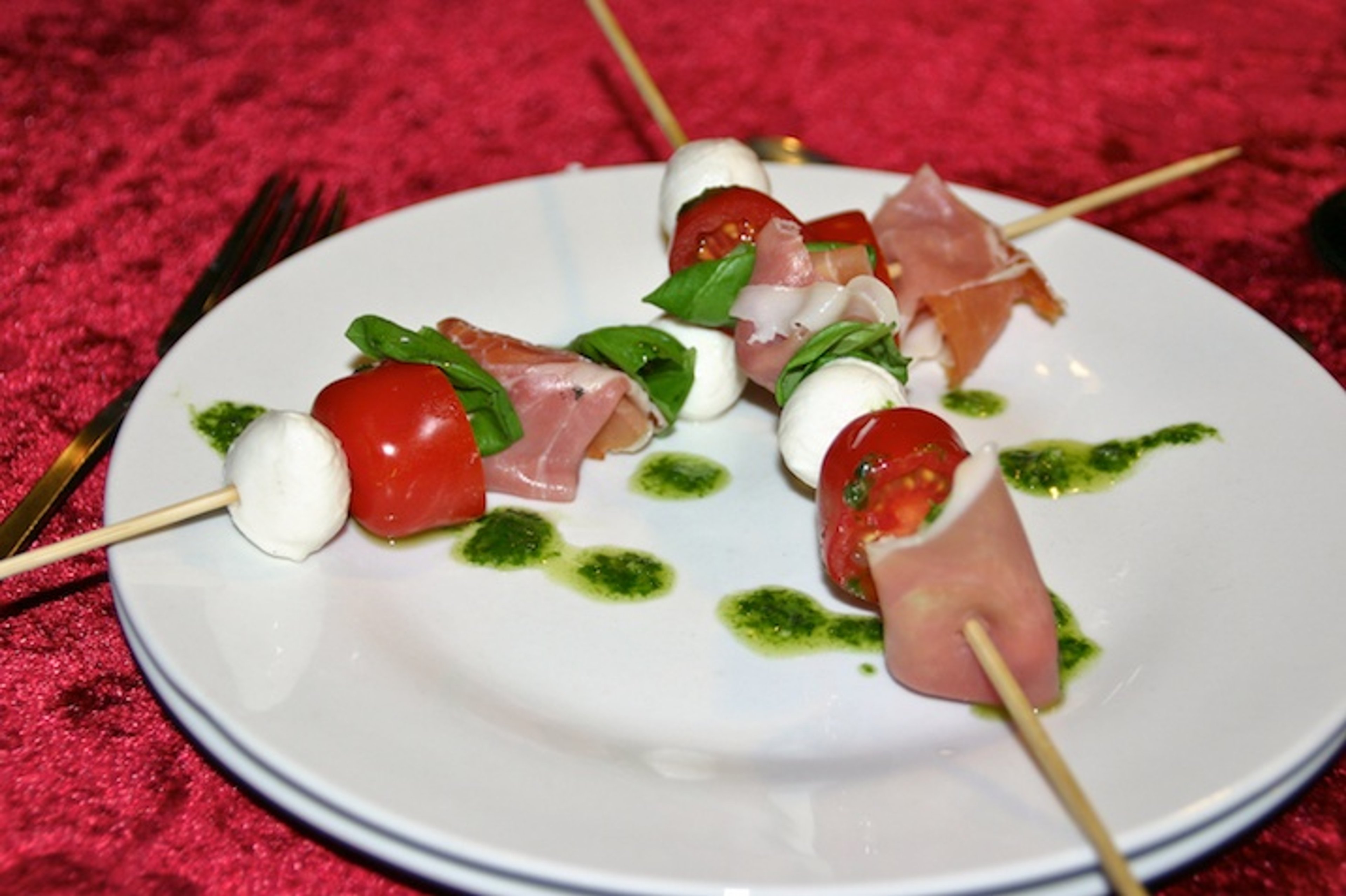 Insalata caprese con prosciutto e olio di pesto su un bastone - eller tomatsalat med skinke og pestoolie på pind