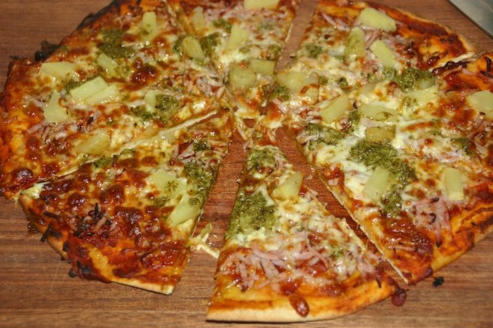 Pizza med fuldkornsbund, tomatsauce, ost, skinke, ananas og pesto