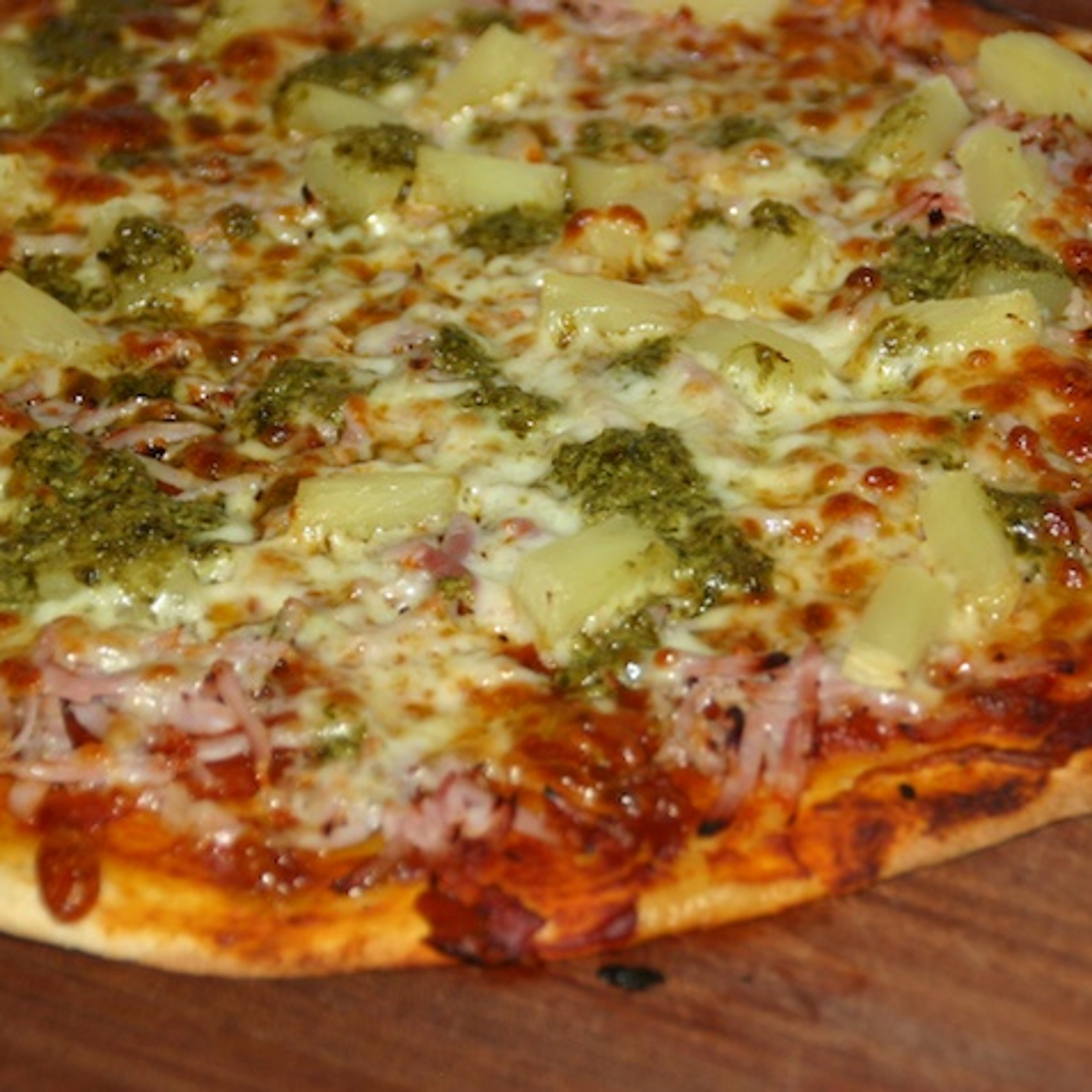 Pizza med fuldkornsbund, tomatsauce, ost, skinke, ananas og pesto