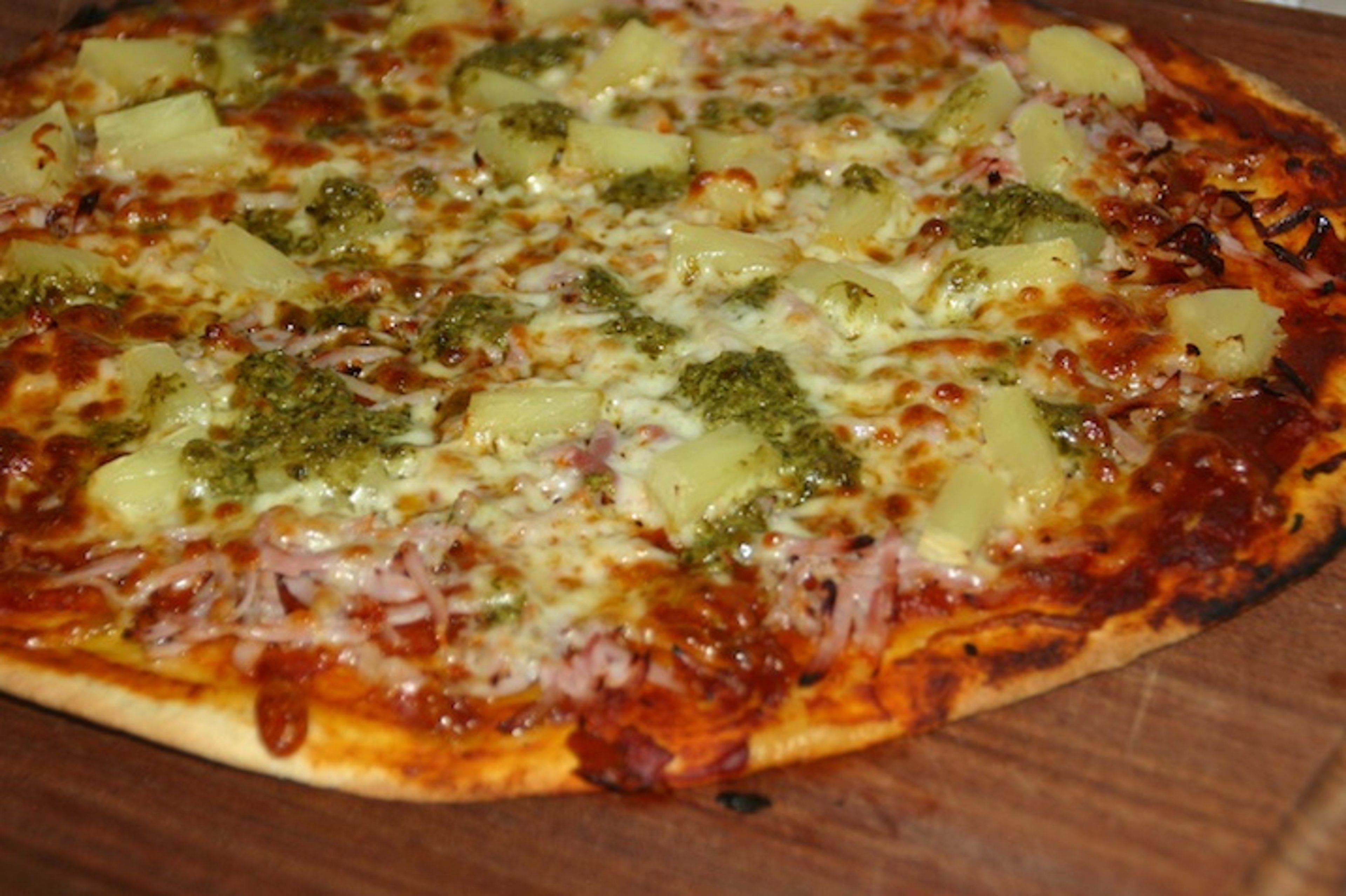 Pizza med fuldkornsbund, tomatsauce, ost, skinke, ananas og pesto