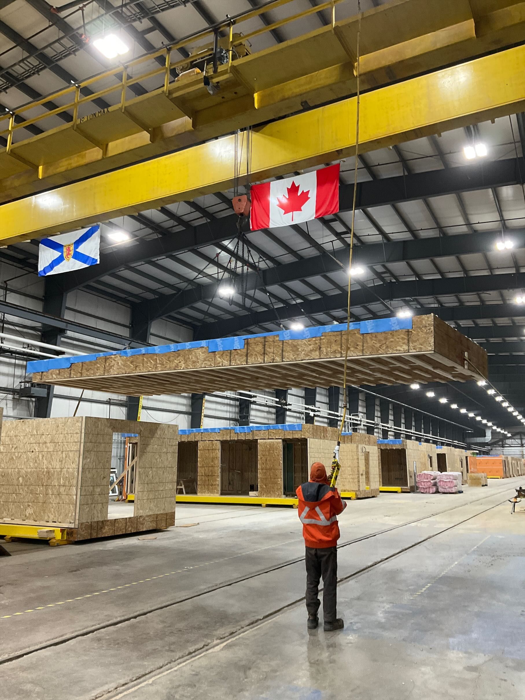 An operator guiding a house module lifted by overhead crane at the Eastcut factory in Trenton