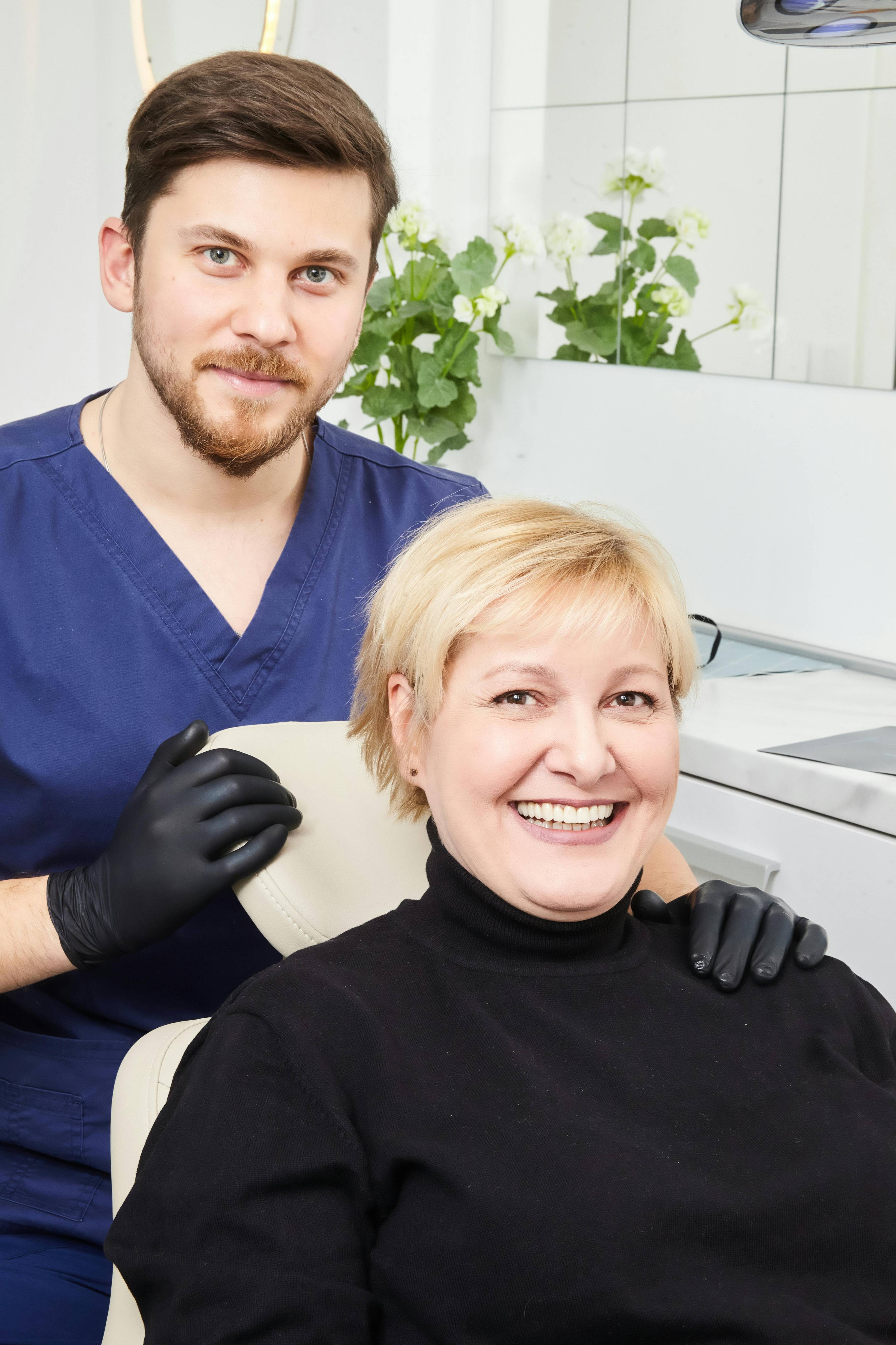 A stock photo of a male dentist with a female patient smiling together