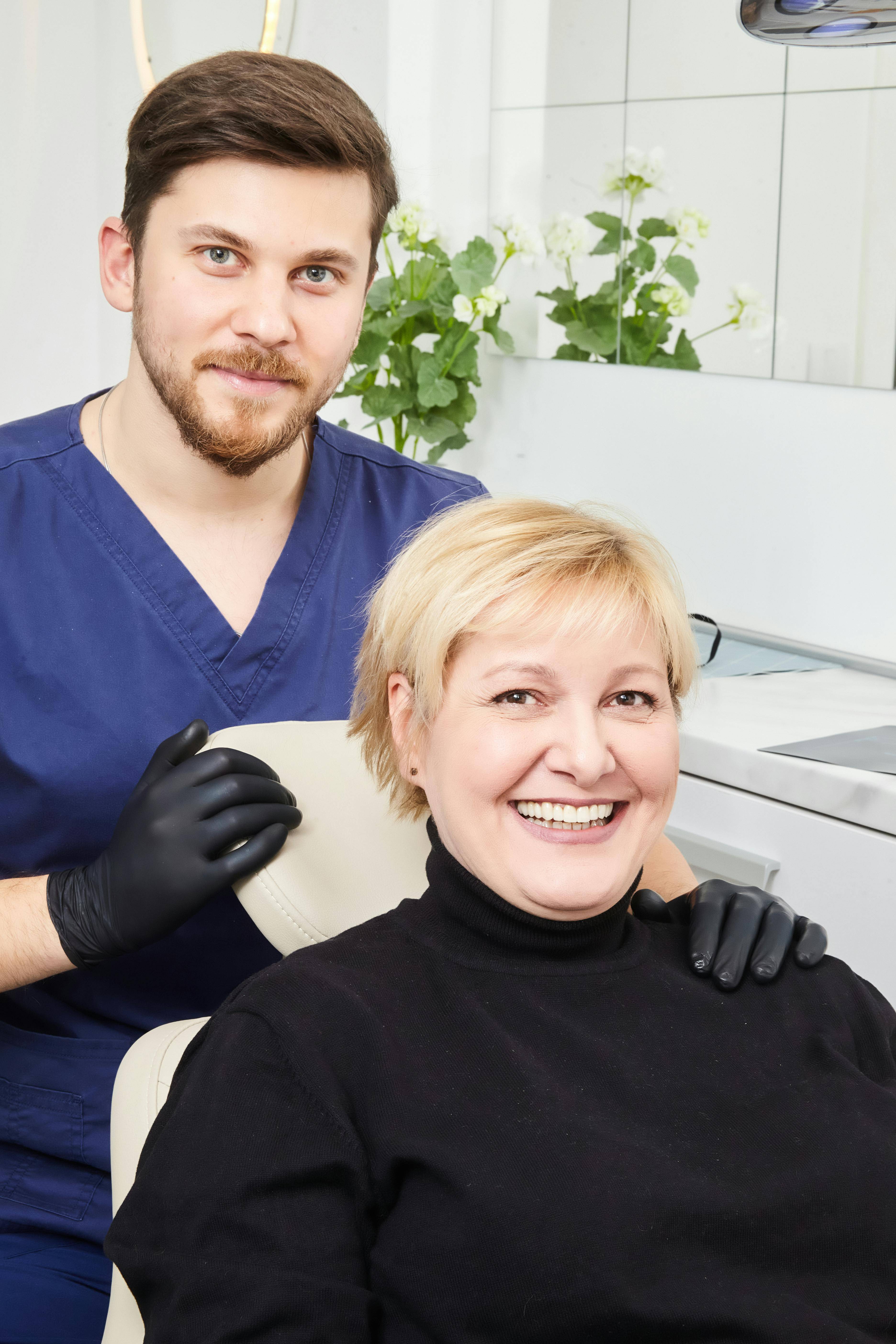 A stock photo of a male dentist with a female patient smiling together