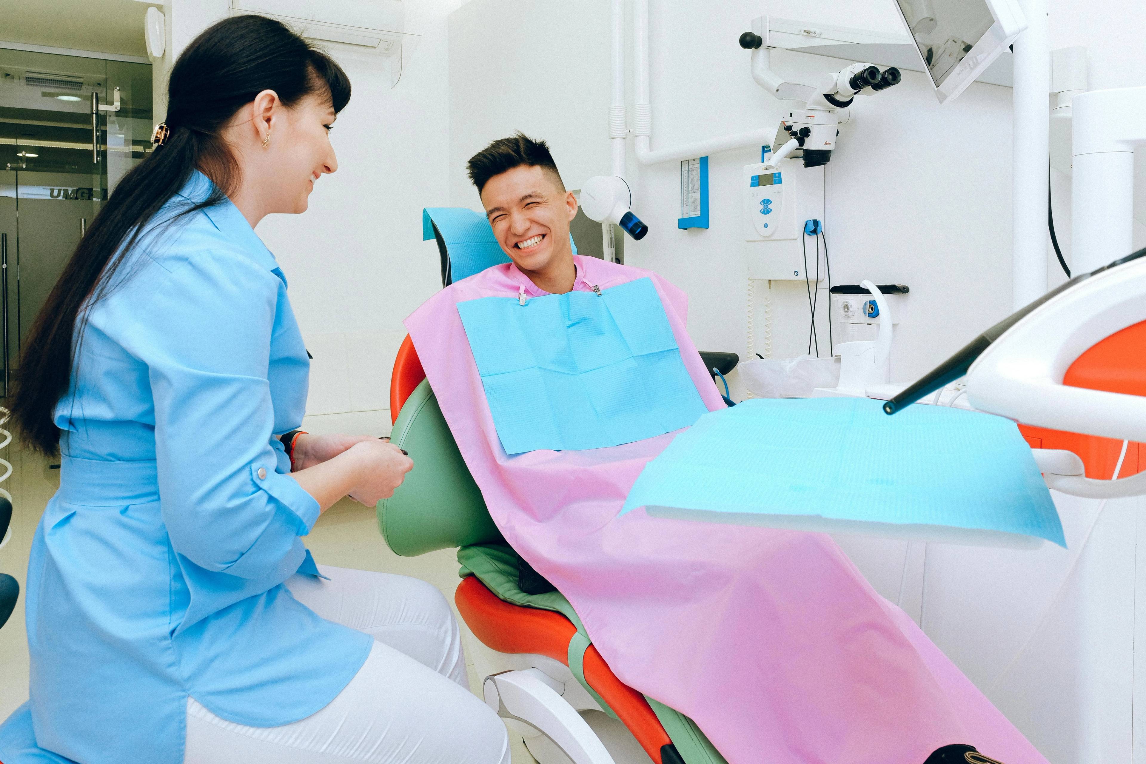 Stock photo of a patient in a treatment chair laughing with his dentist