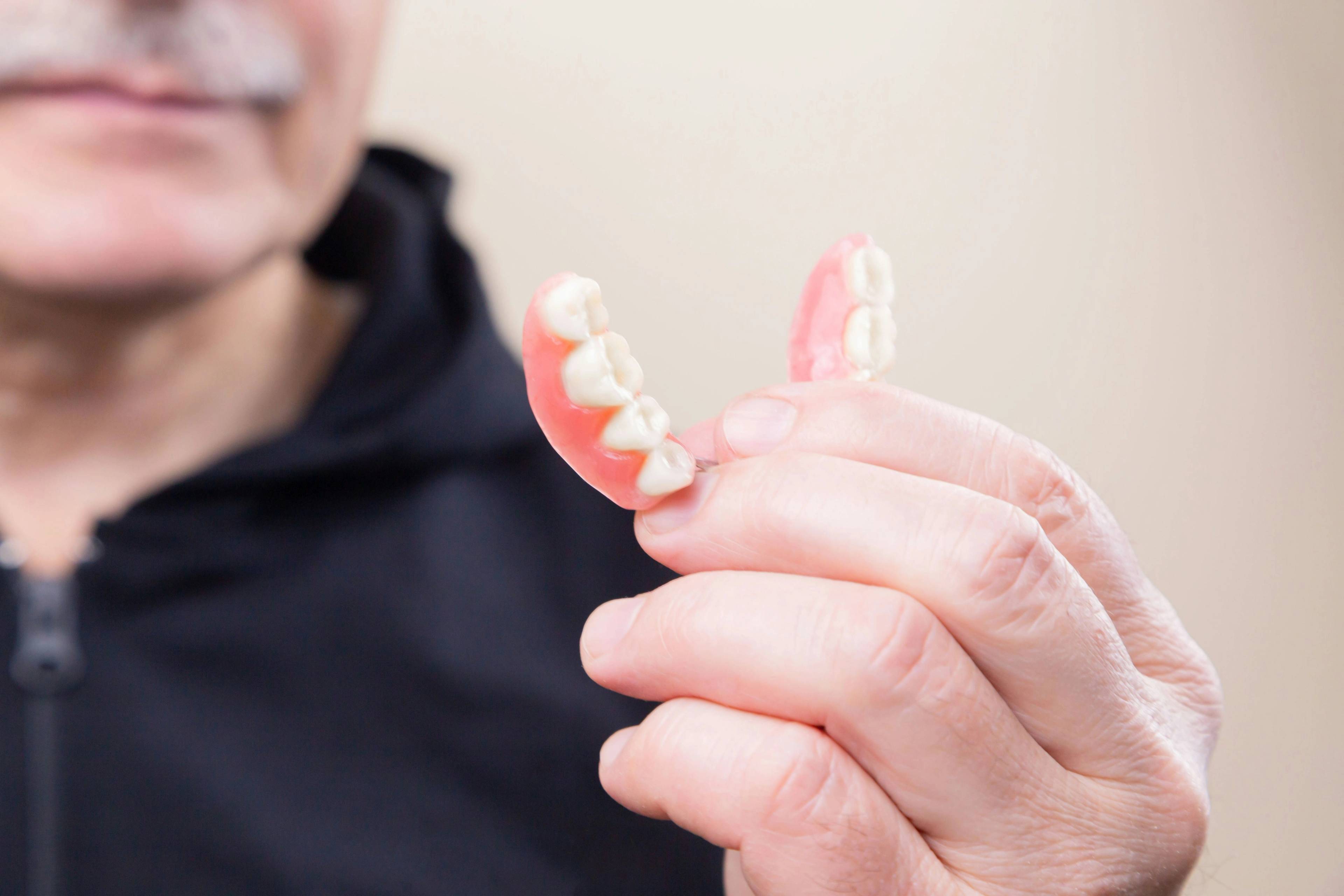 A stock photo of an older patient holding a partial denture