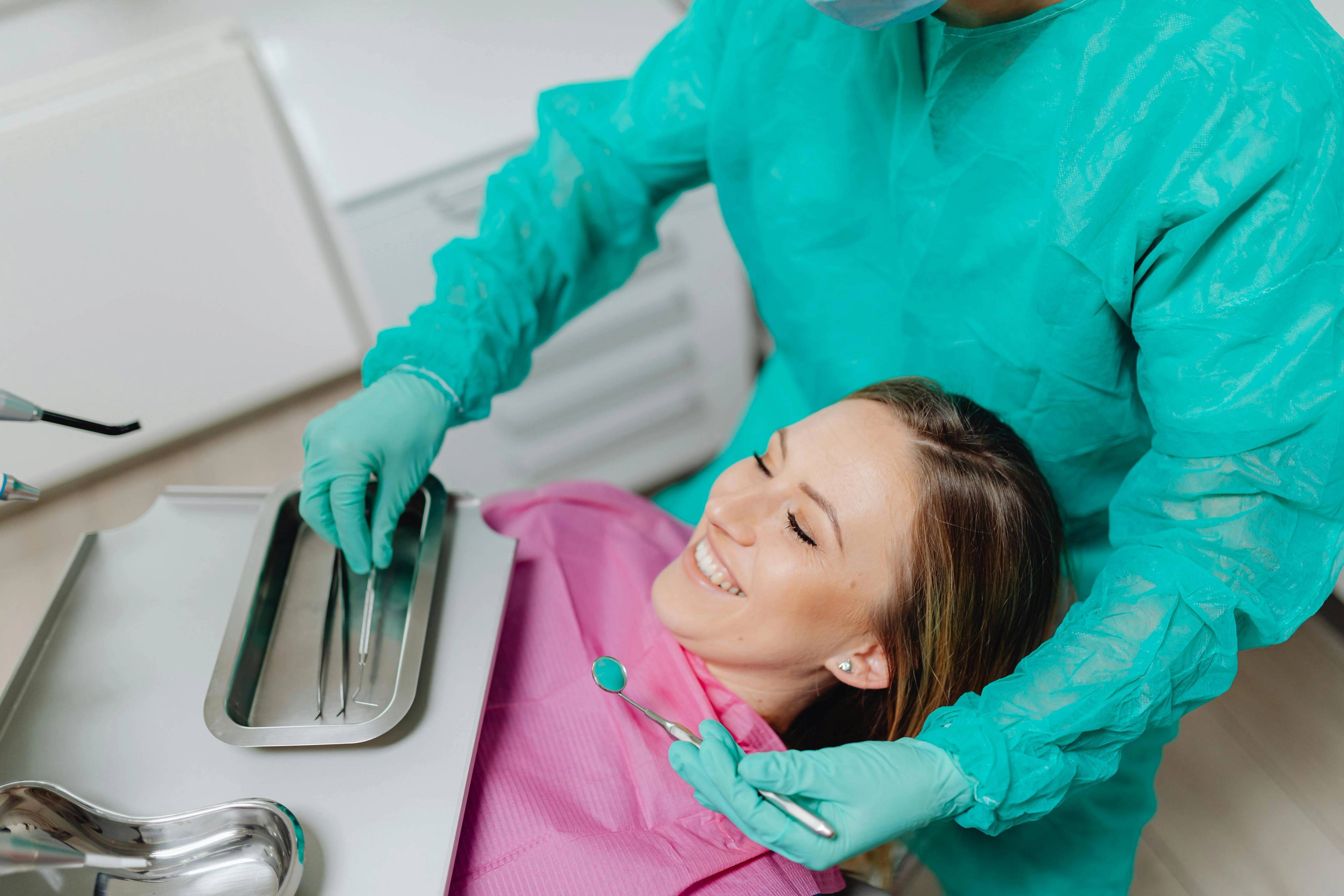 A stock photo of a patient being treated by a dentist in green PPE
