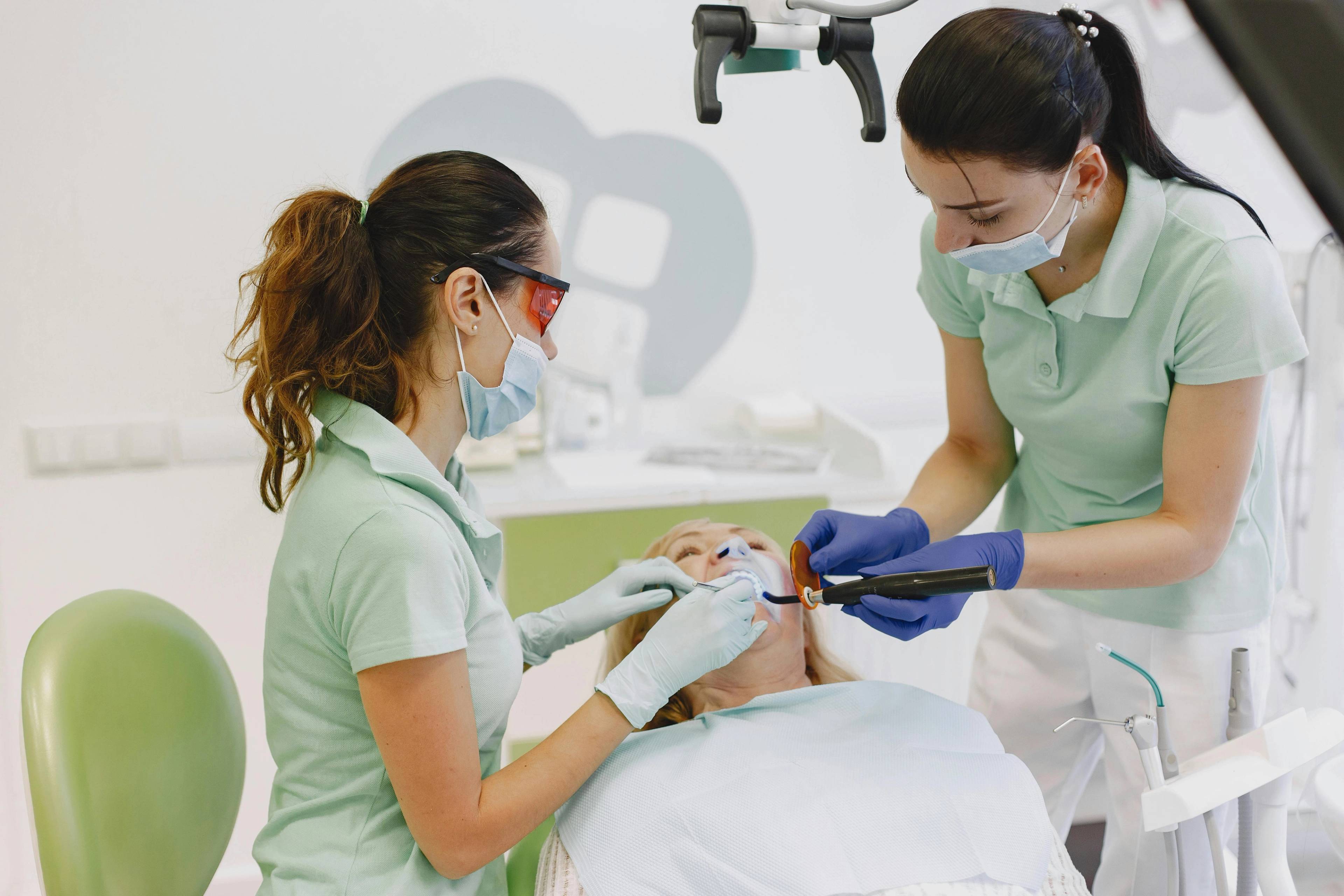 A dentist and a dental nurse work on a patient's teeth