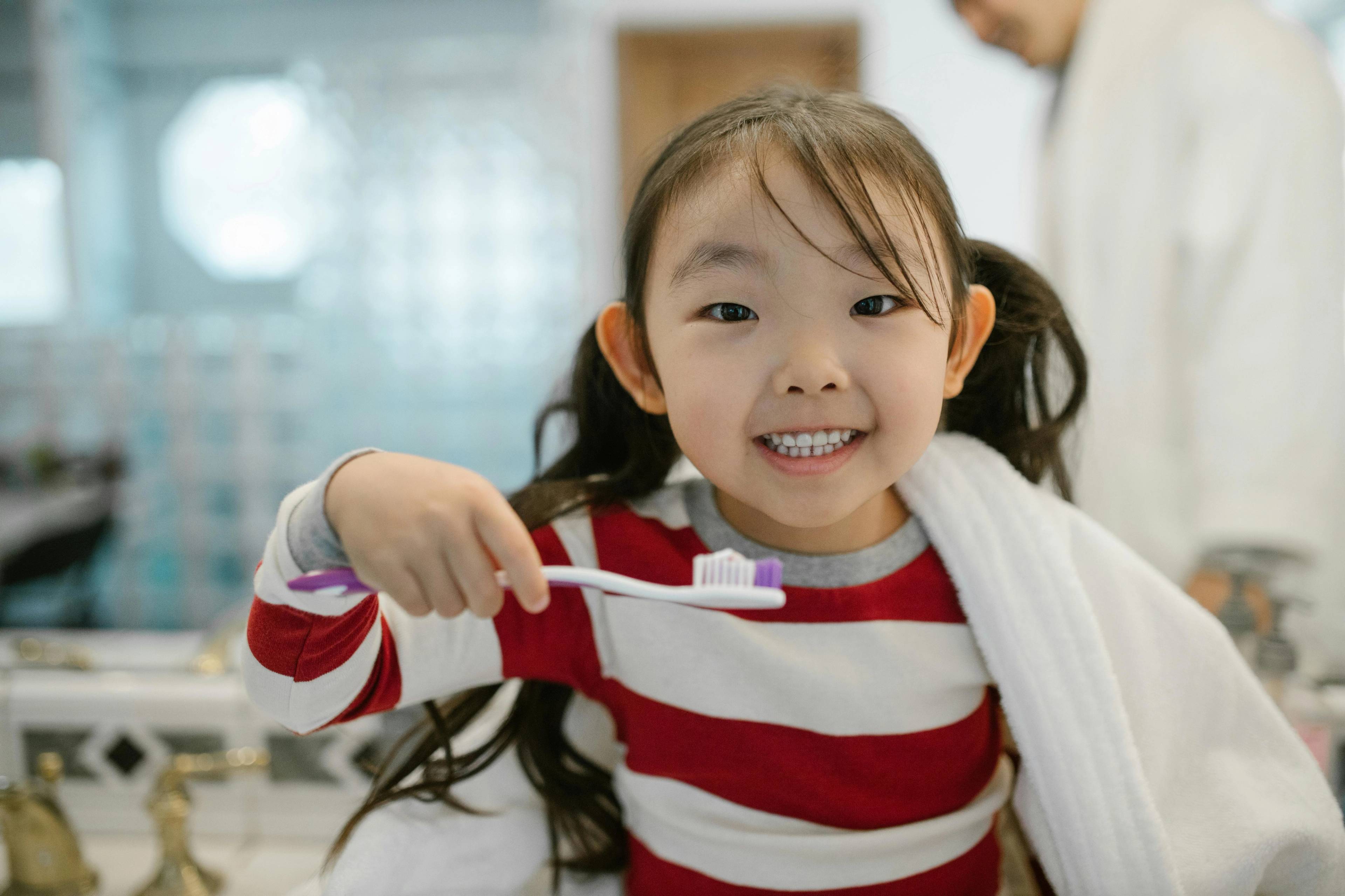 Child cleaning teeth smiling looking toward camera