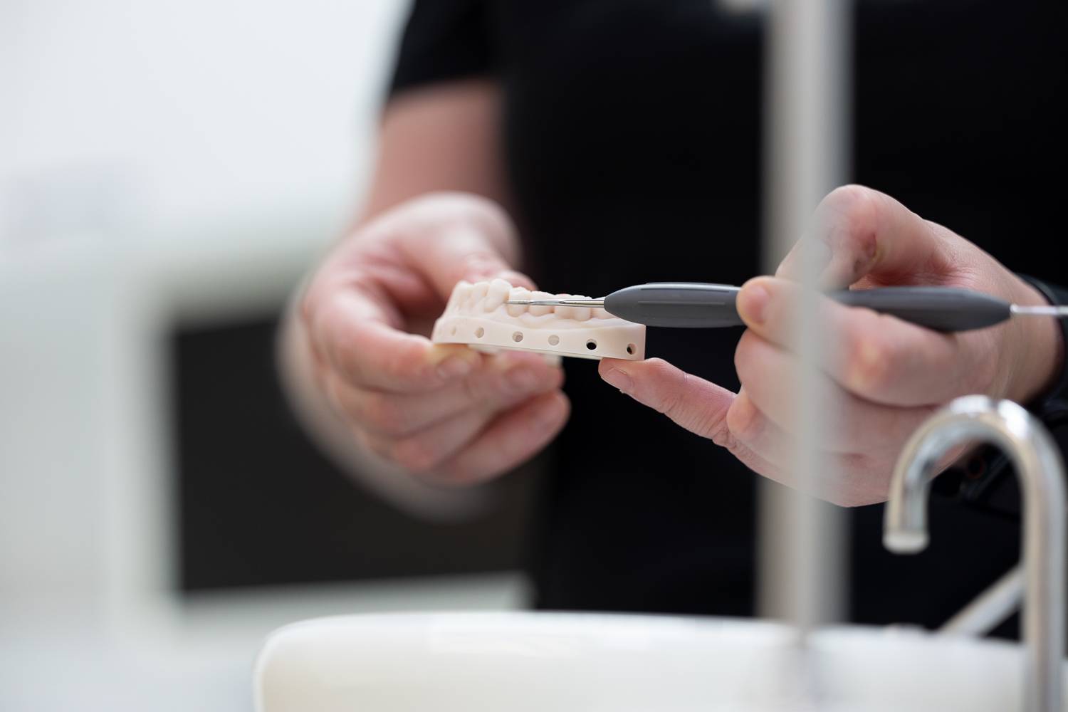 A dentist holding a model of a lower jaw