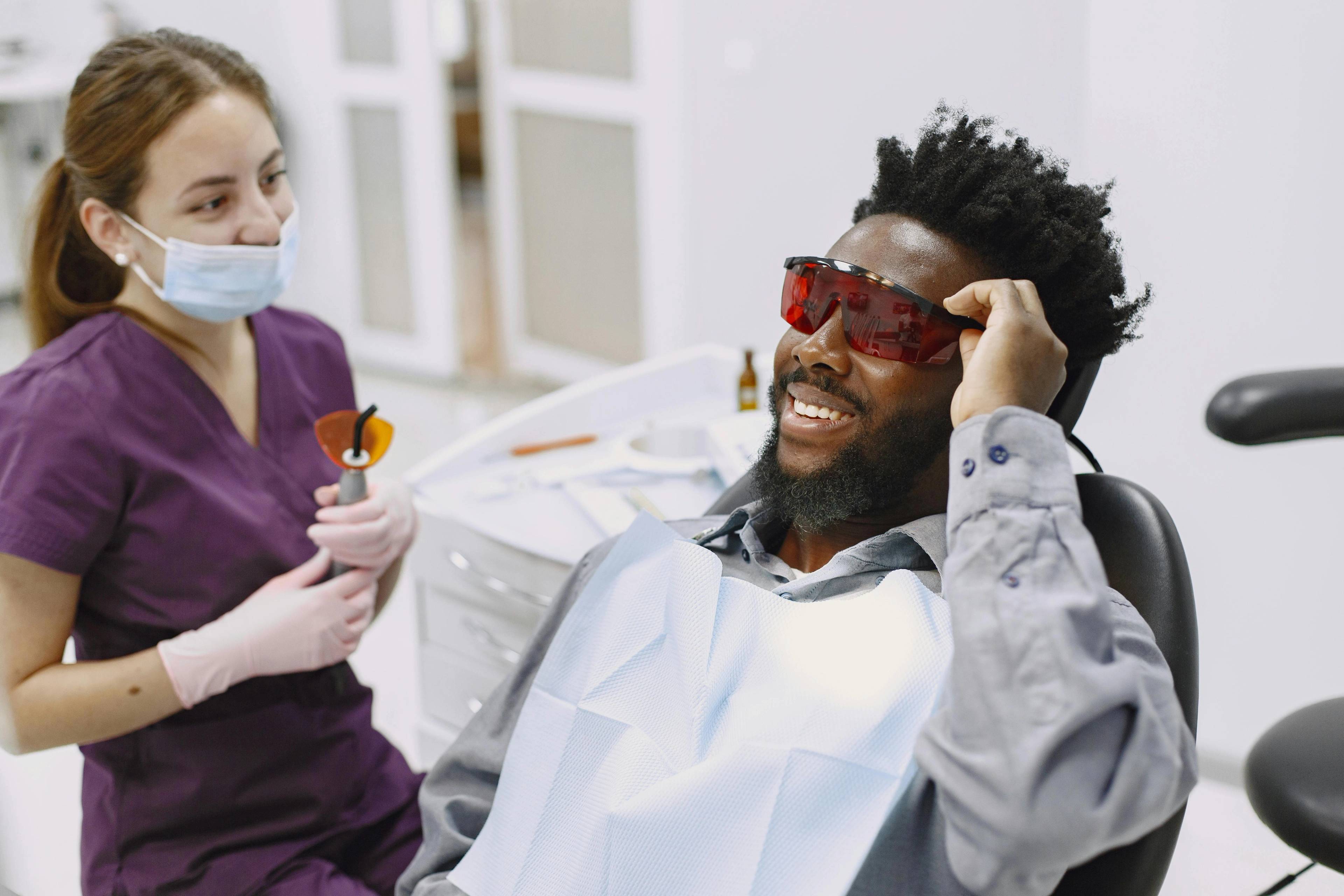 A stock photo of a patient wearing safety glasses in preparation for a teeth cleaning
