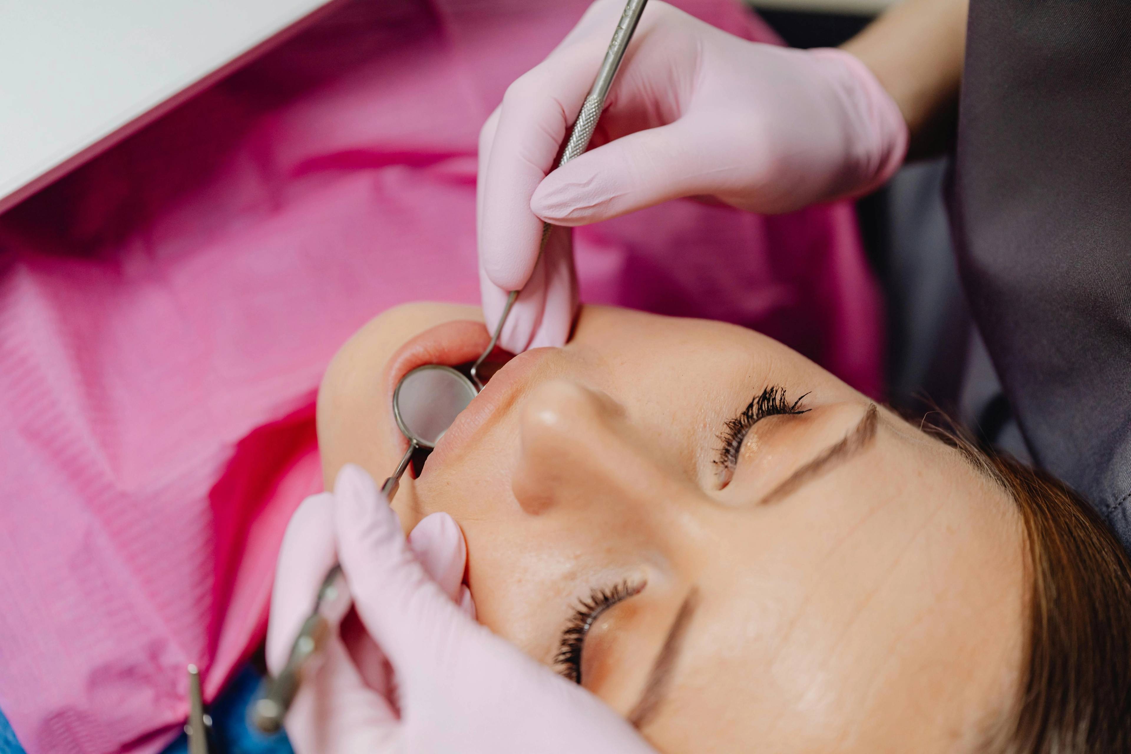 A stock photo of a patient having her teeth examined by a dentist