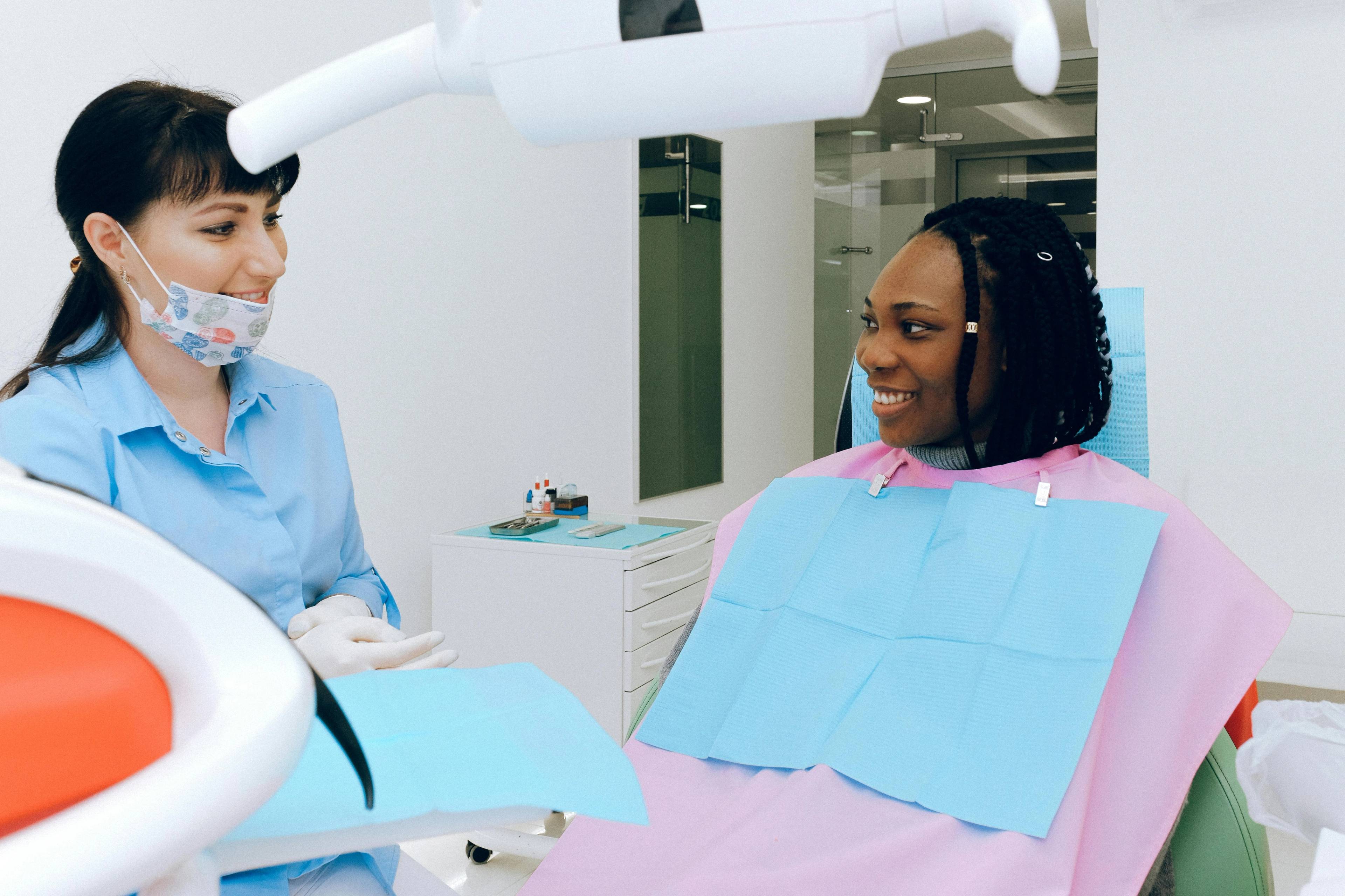 An older female patient smiles as she looks at herself in a hand mirror