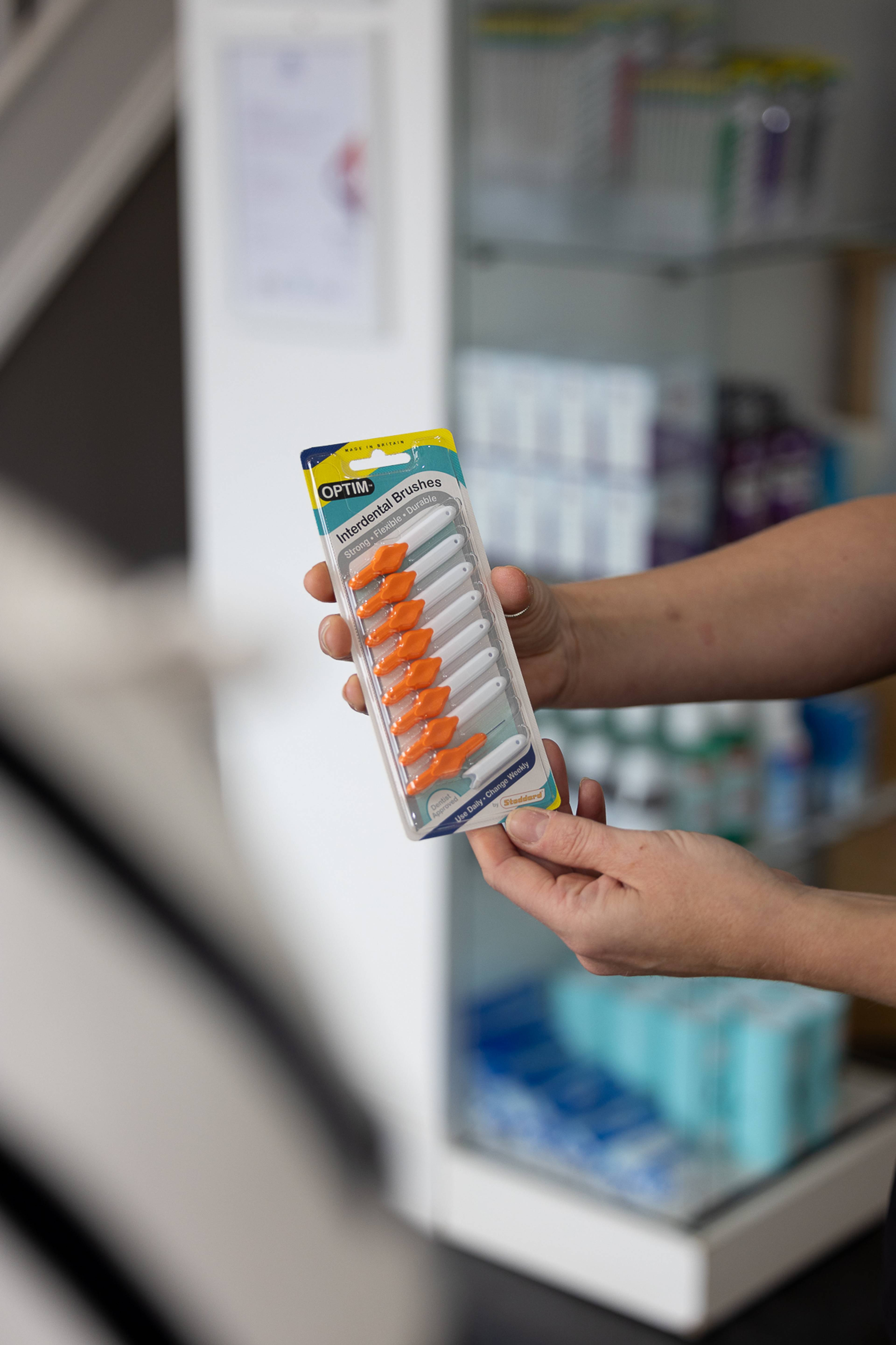 A dentist holding a package of interdental brushes