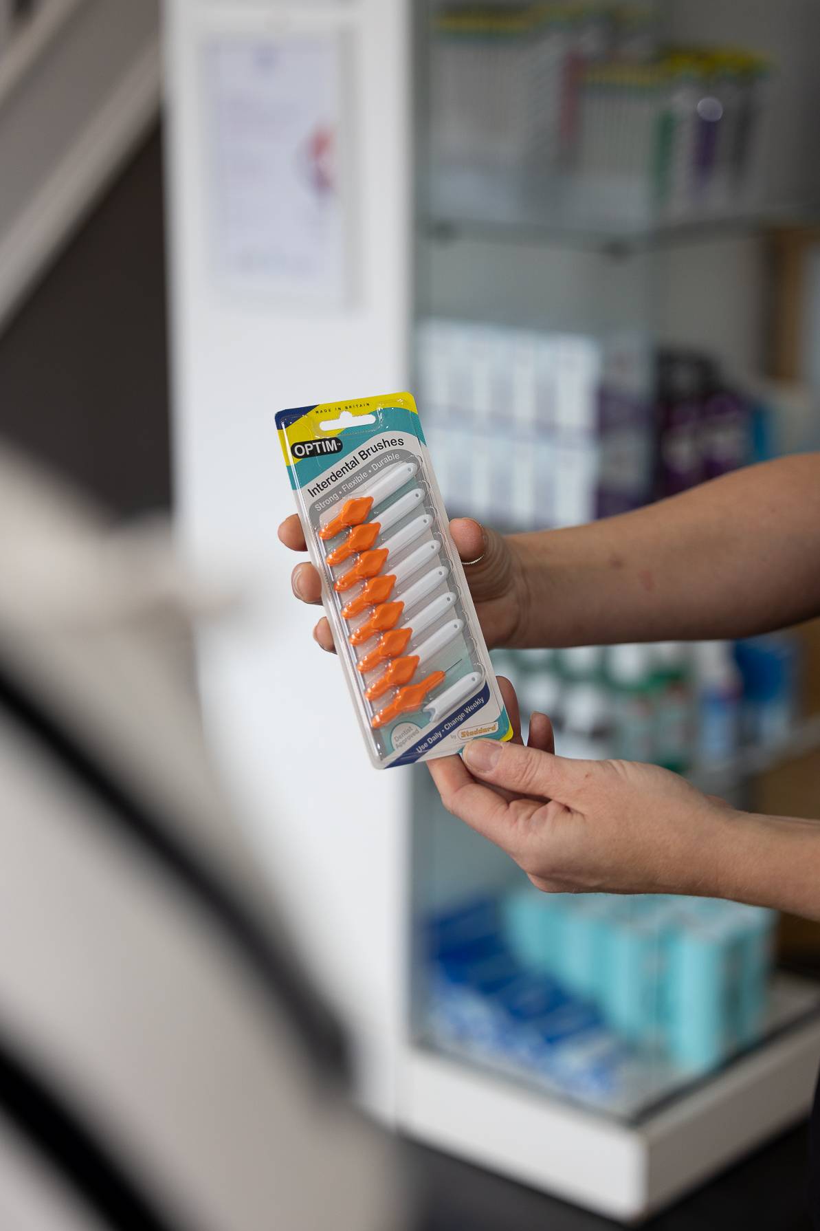 A dentist holding a package of interdental brushes
