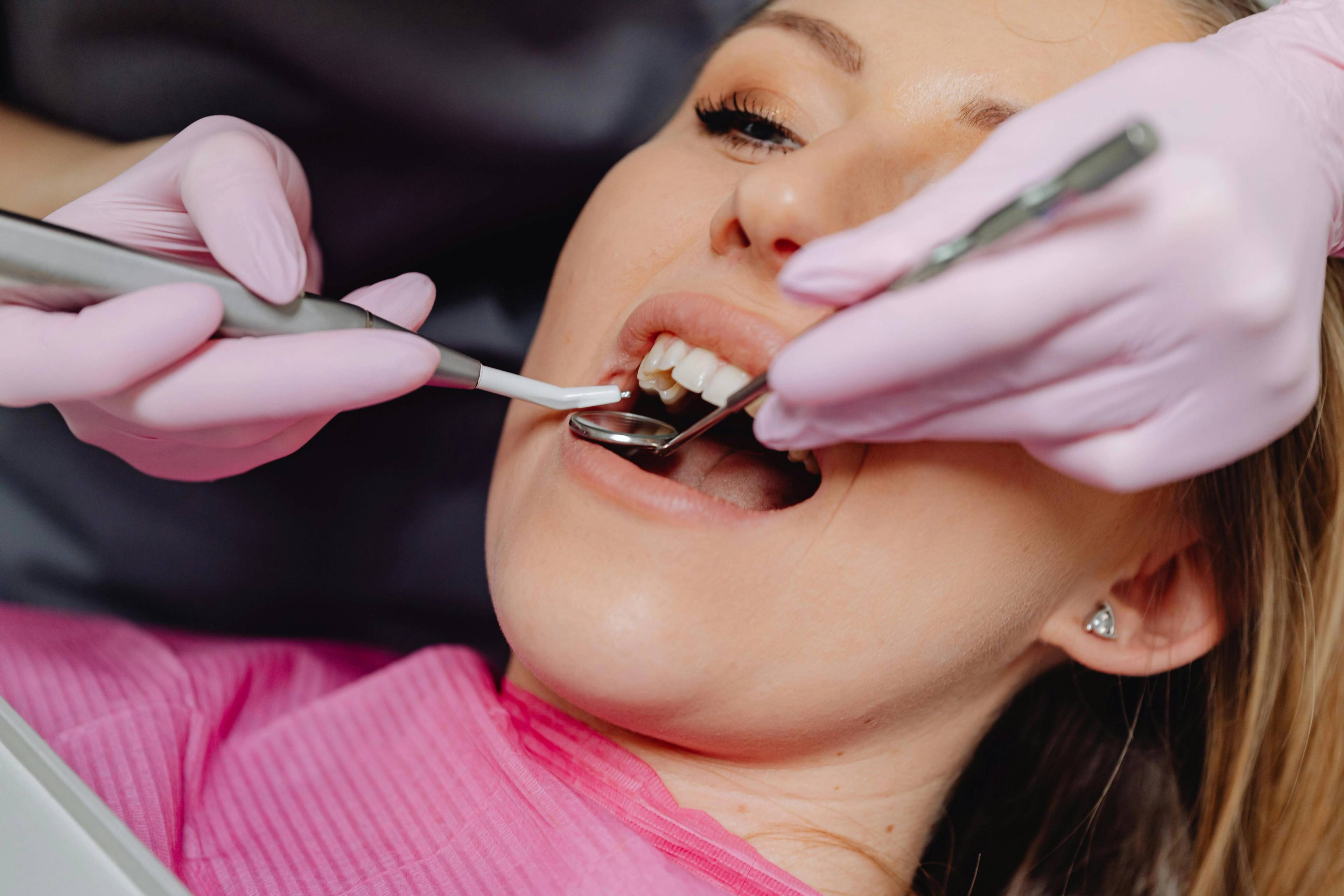 A stock photo of a patient having her teeth examined by a dentist