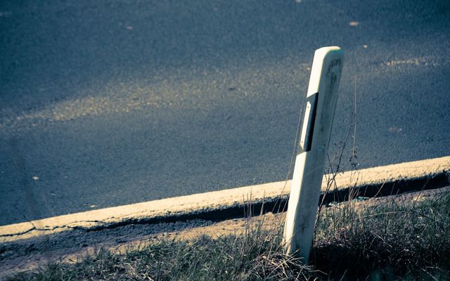 a broken street sign sitting on the side of a road