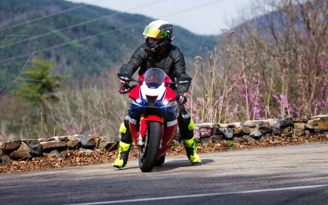 Rider on a red motorcycle on a paved road.