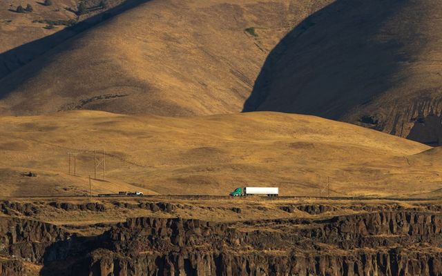 Truck driving on a road through dry hills