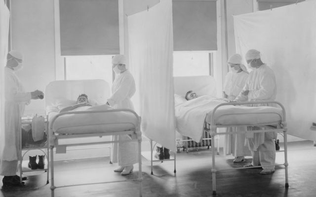 Medical staff attending to patients in hospital beds.