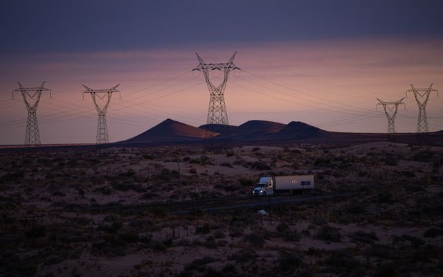 Power lines and truck in desolate landscape at dusk