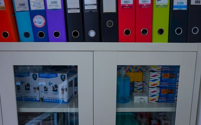a glass door cabinet with a bunch of folders on top of it