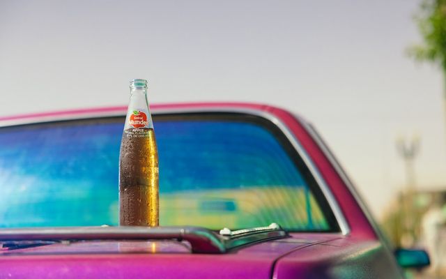 a bottle of beer sitting on top of a purple car