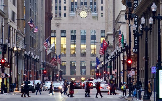 People crossing a street in a city with tall buildings