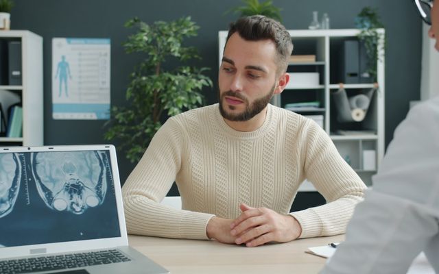 Man talking to doctor with mri scan on laptop