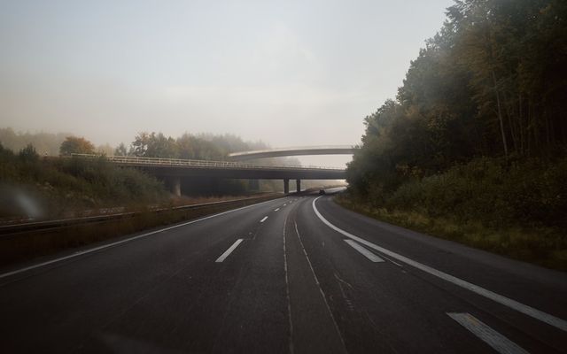a foggy road with a bridge in the distance