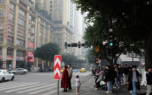 People wait at a city intersection with traffic lights.