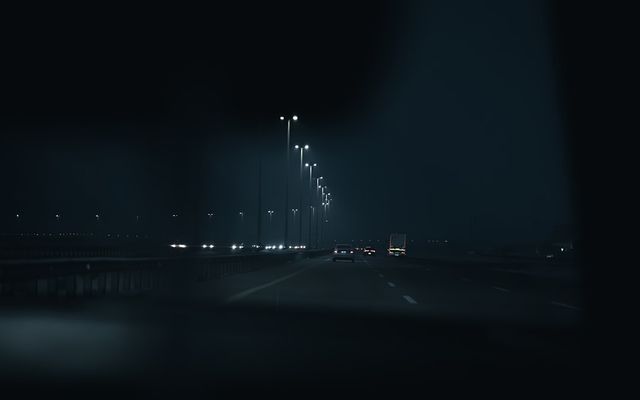 Highway at night with streetlights and distant cars