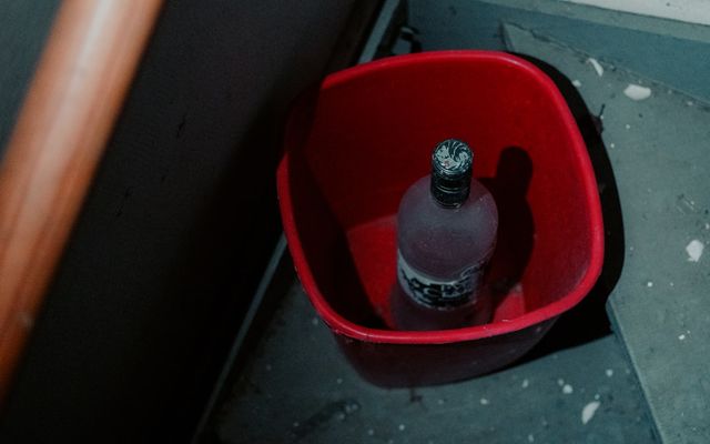 Bottle inside a red bucket on the floor.