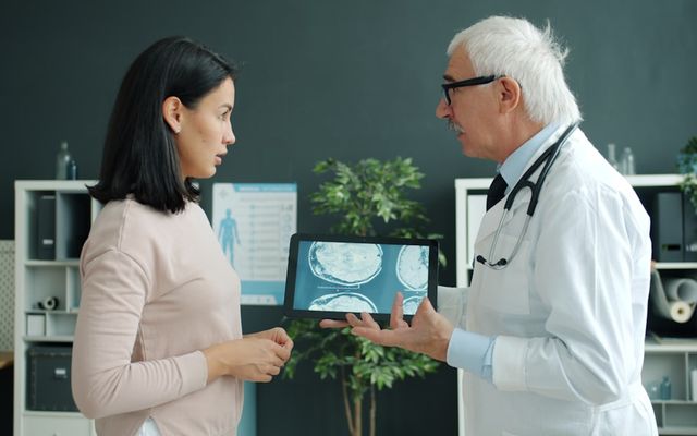 Doctor shows patient medical scan on tablet.