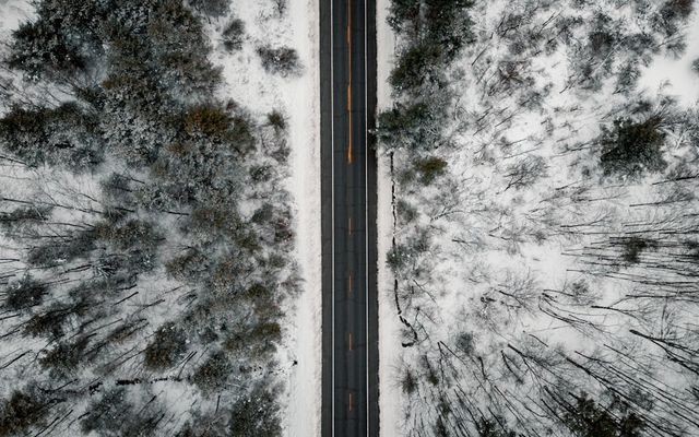 Aerial view of a road through a snowy forest