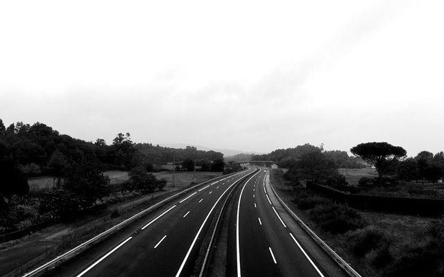 An empty highway curves through a landscape.