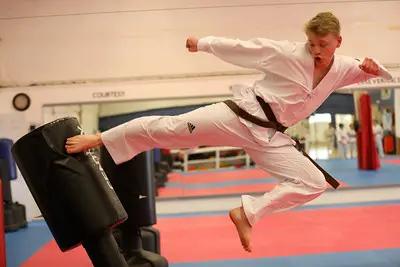 Young martial artist performing a flying kick at Ahn Taekwondo Academy in Blue Ash, sponsored by Gregory S. Young Co., LPA