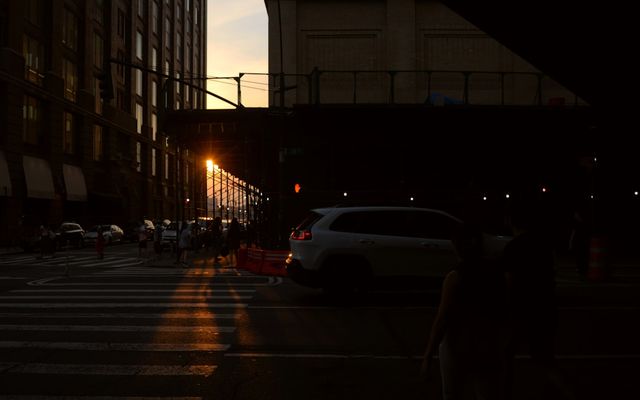 Sunset casts long shadows across a city street.