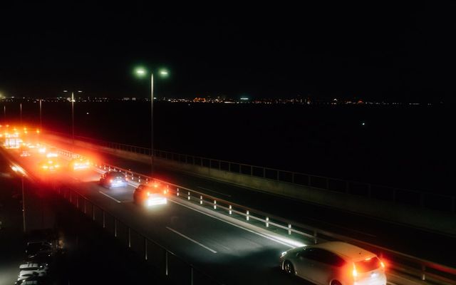 Cars driving on a highway at night with city lights.