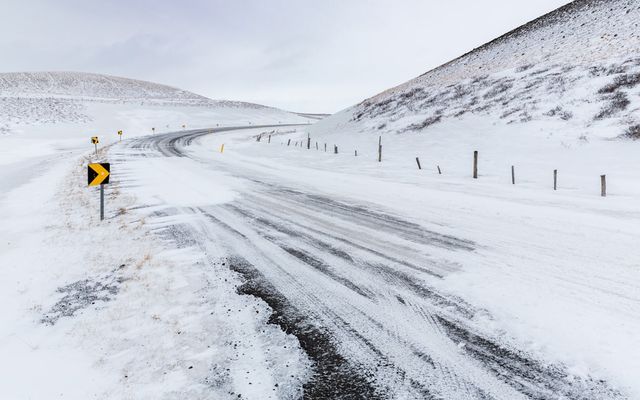 A snow-covered road winds through a barren landscape.