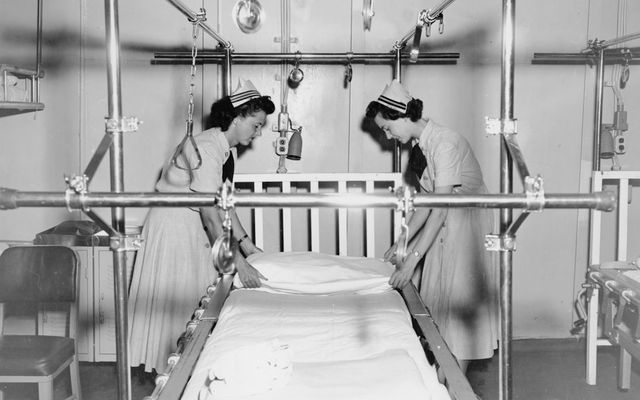 Nurses preparing a hospital bed with traction apparatus.