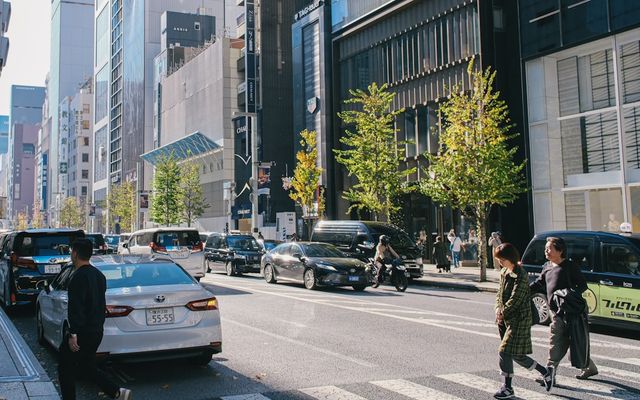 People crossing street in a city with cars.