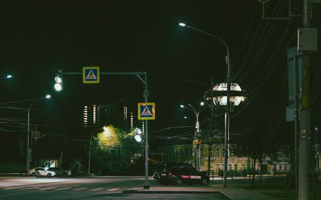 Streetlights illuminate a city intersection at night.