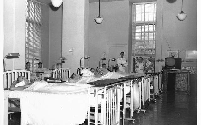 Patients in hospital beds with nurses nearby