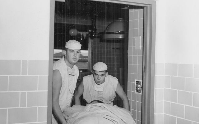 Two medical professionals transport a patient on a gurney.