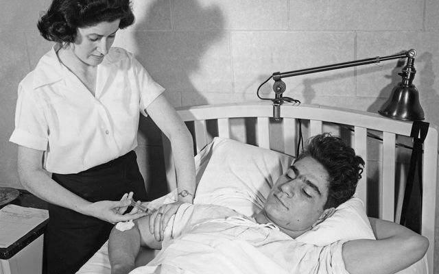 Nurse gives injection to patient in bed