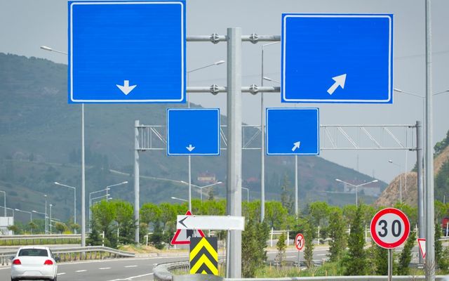 Several blue road signs with arrows on a pole.