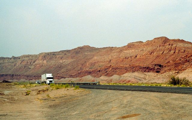 Truck driving on a highway with rocky hills.