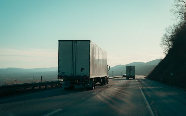 Two semi-trucks driving on a highway.